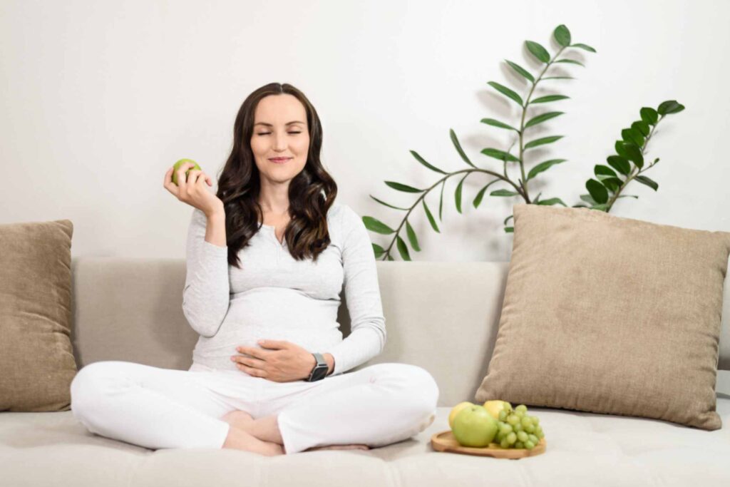 jpeg optimizer healthy eating during pregnancy pregnant caucasian woman eats green apples sitting couch healthy snack with fruit - Fit Kilter